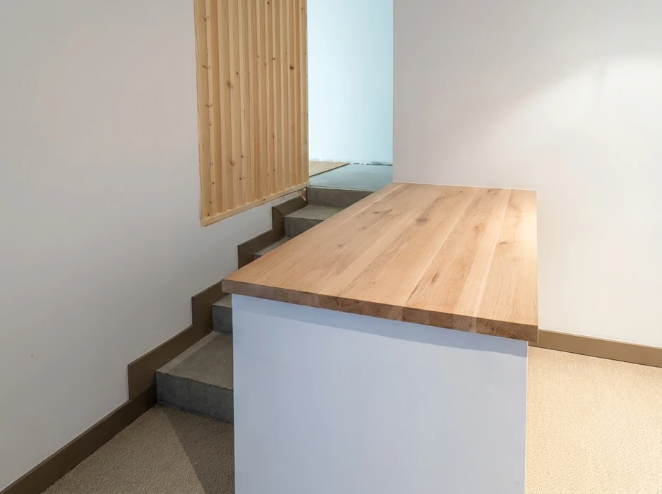 Escalier intérieur en béton avec contremarches grises, surmonté d'un plan de travail en chêne massif abouté