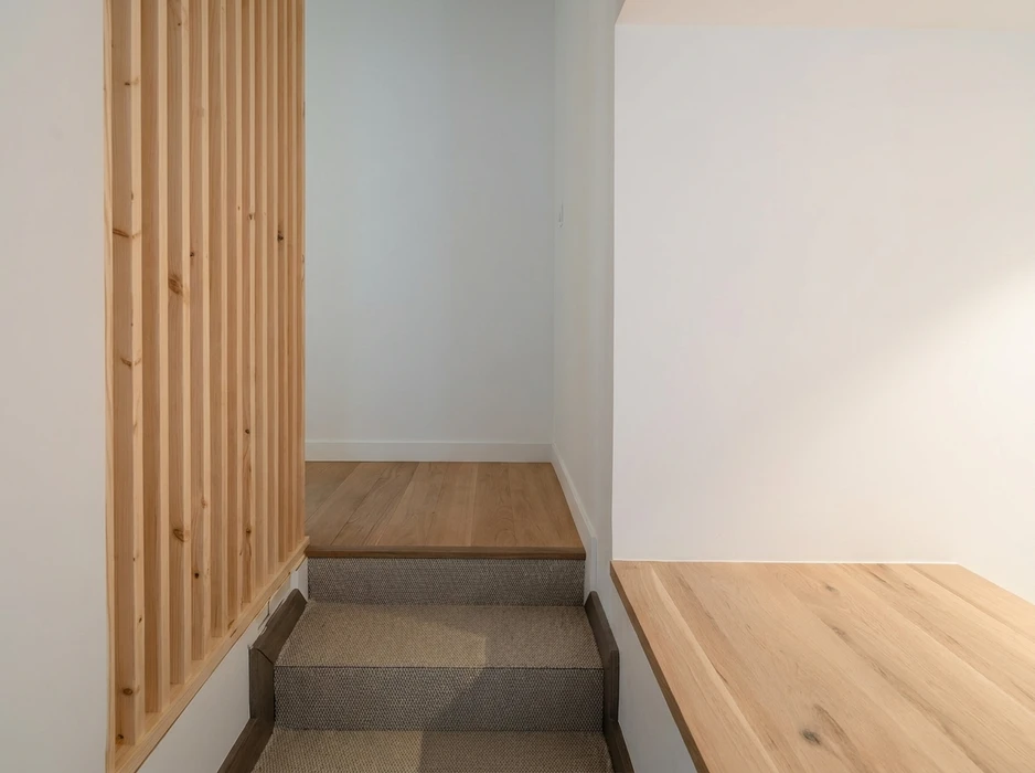 Escalier intérieur moderne avec marches recouvertes d'un revêtement en moquette bouclée grise, nez de marche en chêne massif huilé