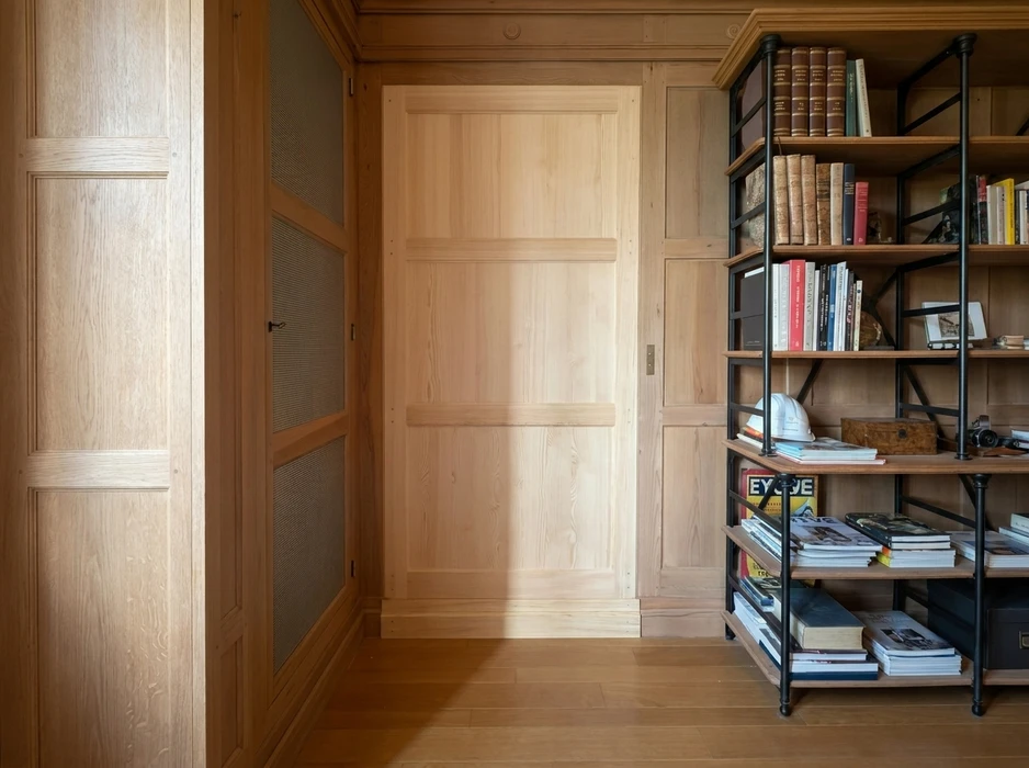 Intérieur raffiné avec boiseries murales en chêne naturel, porte affleurante à panneaux en pin clair intégrée dans un mur boisé