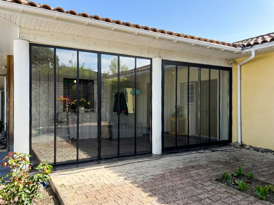 Véranda ou extension vitrée extérieure d'une maison individuelle, vue de la cour pavée