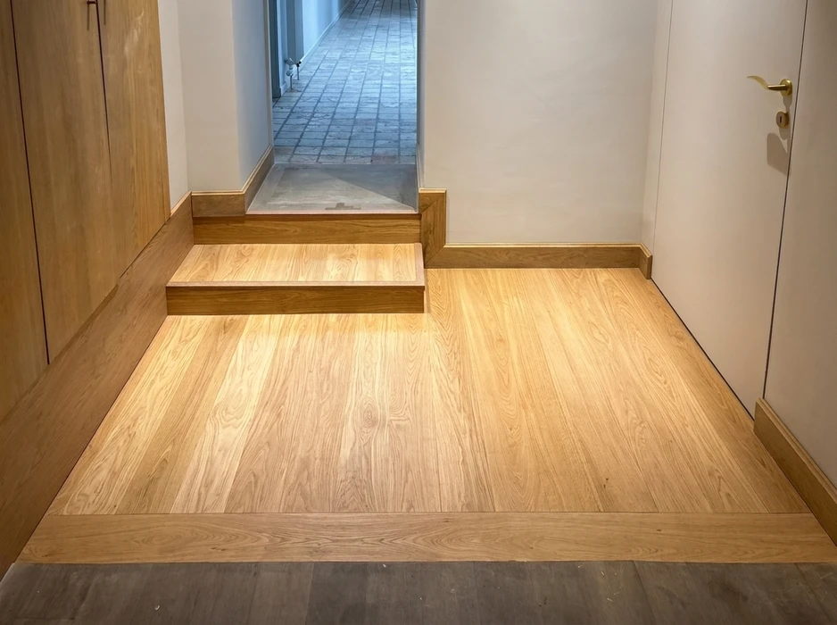 Entrée intérieure avec escalier à deux marches en parquet massif chêne naturel huilé, pose en lames larges à joints vifs