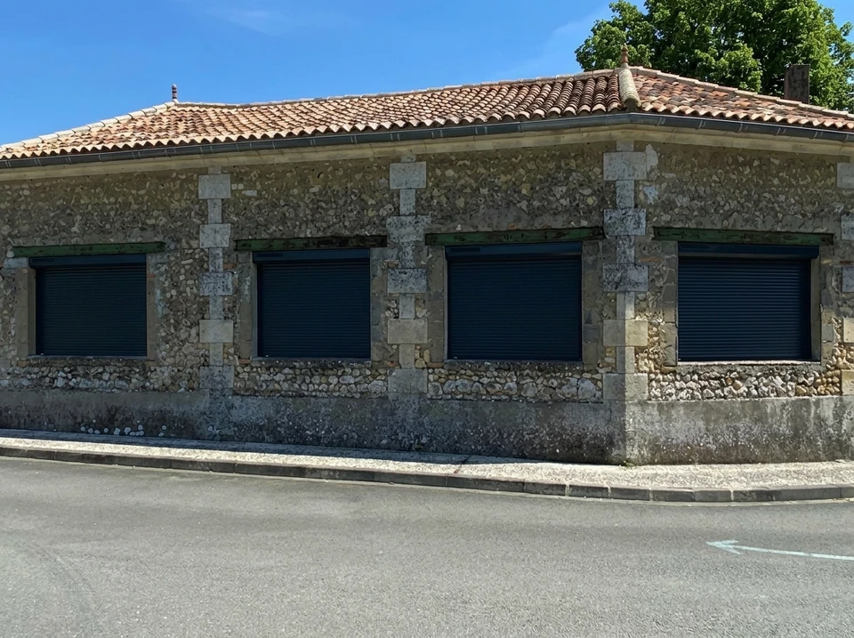Artisan menuisier travaillant dans un atelier de menuiserie, utilisant un rabot sur une pièce de bois posée sur un établi