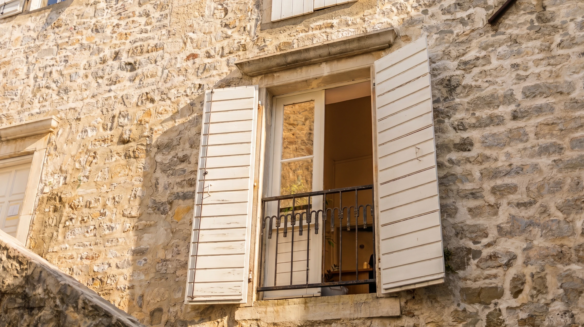 Façade extérieure de maison traditionnelle avec deux fenêtres à volets battants bruns ornés de ferrures décoratives